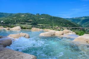 - une piscine avec des rochers et de l'eau dans une montagne dans l'établissement Tenuta Pian D'Attesio - Agriturismo, à Castelletto Soprano