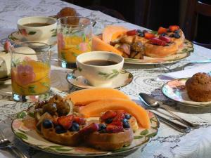 einen Tisch mit Teller mit Speisen und Tassen Kaffee in der Unterkunft Serendipity Bed and Breakfast in Saugatuck