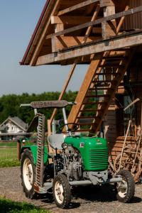 a green tractor parked in front of a building at Tourist Farm Firbas in Cerkvenjak