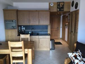 a kitchen with wooden cabinets and a table and chairs at La Perle Des Alpes C2 in Villard-sur-Doron