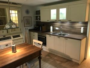 a kitchen with white cabinets and a wooden table at Ferienwohnung am Hörnle in Bad Kohlgrub