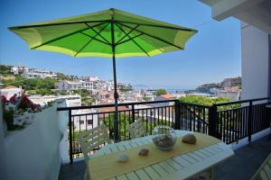 a table with a green umbrella on a balcony at Theodora in Patitiri