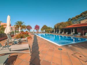 a swimming pool with chairs and umbrellas at a resort at Ocean Gardens in Funchal
