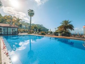 a large blue swimming pool with palm trees in the background at Ocean Gardens in Funchal