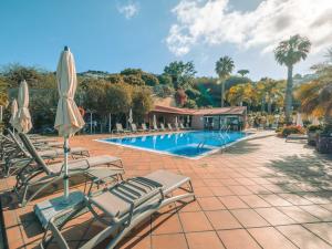a swimming pool with lounge chairs and umbrellas at Ocean Gardens in Funchal