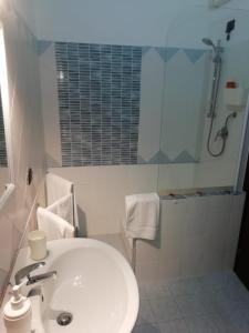a white bathroom with a sink and a shower at Fontanarossa Airport Home in Catania