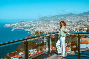 a woman standing on a balcony overlooking a city at Ocean Gardens in Funchal