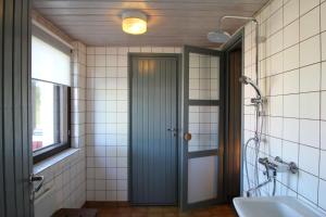 Un baño con puerta, bañera y ventana. en Villa Taikinajoki, LaatuLomat, en Pertunmaa 26 fotos más