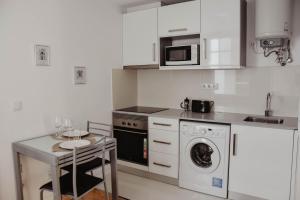 a kitchen with a washing machine and a table at Apartamento central, moderno e luminoso - Self check in in Coimbra