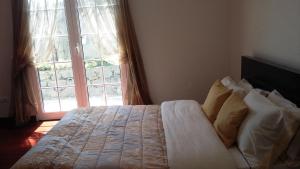 Casa Shalom في Faial: سرير في غرفة نوم مع نافذة كبيرة