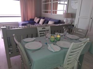 a dining room table with plates and wine glasses at 504 Witsand in Bloubergstrand