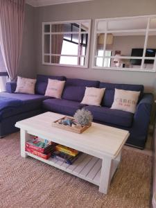 a living room with a blue couch and a coffee table at 504 Witsand in Bloubergstrand