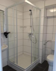 La salle de bains est pourvue d'une douche en verre et de toilettes. dans l'établissement Gästehaus Lutschounig, à Faak am See