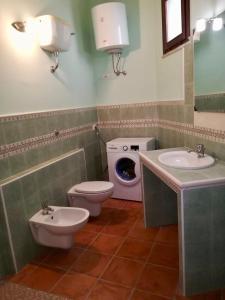 a bathroom with a toilet and a sink and a washing machine at Sa Corti Antiga Apartment in SantʼAntìoco