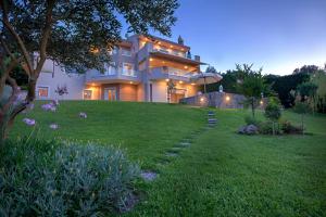 a large house on a hill with a green lawn at Marina View Luxury Home in Gouvia