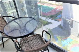 uma mesa e cadeira numa varanda com vista para um campo de ténis em Modern One Bedroom Condo at Mactan, Cebu em Mactan