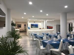 um salão de banquetes com mesas azuis e cadeiras brancas em Hotel Barbarossa em Porto Azzurro
