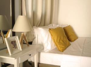 a white couch with yellow pillows and a table with a lamp at Studio Panagiota - Oasis holiday houses in Kókkinos Pírgos