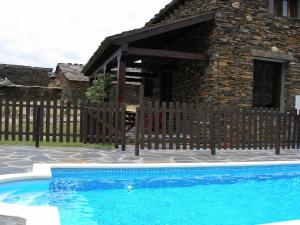 ein Pool vor einem Haus mit einem Holzzaun in der Unterkunft La Pizarra Negra in Campillejo