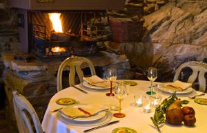 a table with plates and wine glasses and a fireplace at CASA ALDABA in La Hiruela