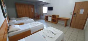 a hotel room with two beds and a television at Hotel Gemeos in São Mateus