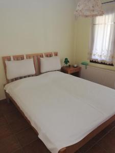 een groot wit bed in een kamer met 2 ramen bij Oneiro in Vathírrevma