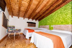 1 dormitorio con 2 camas y pared verde en Albergue Santa Marina en Buelna