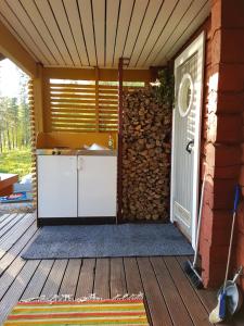 a porch with a white door and a wall of logs at Salen Saunamökki in Ranua
