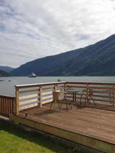 eine Holzterrasse mit einem Tisch und Stühlen auf dem Wasser in der Unterkunft Bazyl Apartment in Folkedal