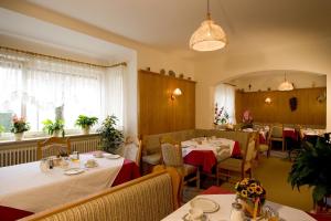 un comedor con mesas, sillas y ventanas en Kurhotel Dornröschen en Bad Wörishofen