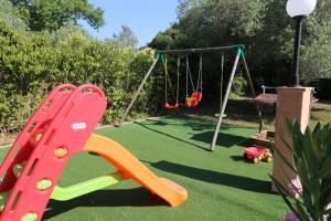 un parque infantil con tobogán y columpio en Villa Argo 3 - Beachfront, Big gardens, Location! en Pefkohori