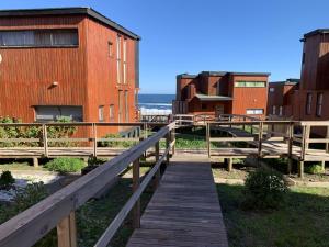 une promenade en bois menant à un bâtiment et à la plage dans l'établissement Pichilemu Loft 51, à Pichilemu