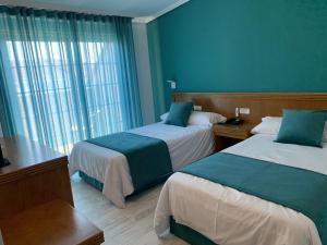 a hotel room with two beds and a window at Nueva Colina in Tomiño