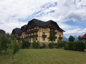 a large building with a grass field in front of it at Apartmán Erika in Veľká Lomnica