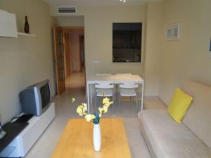 Una sala de estar con un jarrón de flores sobre una mesa. en Apartamentos Sitges, en Sitges