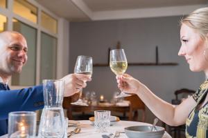 Zwei Leute sitzen an einem Tisch und trinken Wein. in der Unterkunft Hotel Viking Aqua Spa & Wellness in Sæby