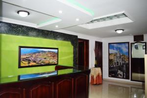 sala de estar con pared verde y TV en Hotel Londres, en Pasto