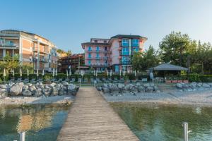 un puente de madera sobre una masa de agua con edificios en Kriss Internazionale Hotel en Bardolino