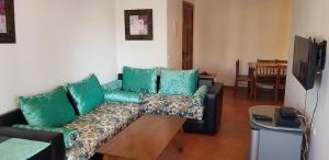 sala de estar con sofá y almohadas verdes en Alcudia Smir 3 chambres, en M'diq