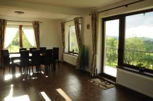 a dining room with a table and chairs and windows at Casa din Livada in Predeluţ