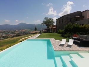 a swimming pool with two chairs and a house at Serre Alte Landscape Luxury Rooms in Matelica
