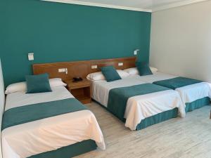 twee bedden in een hotelkamer met blauwe muren bij Nueva Colina in Tomiño