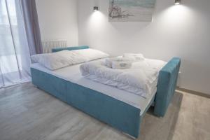 niebieskie łóżko z białą pościelą i poduszkami w obiekcie Perfekt Apartments 5 Mórz Sianożęty w Sianożętach