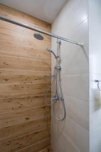 a shower in a bathroom with a wooden wall at New Gudauri Suites N317 in Gudauri