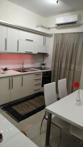 a kitchen with white cabinets and a table with chairs at LAVIM Apartments in Sikia