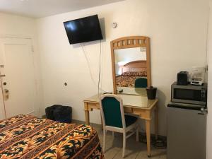 1 dormitorio con escritorio, espejo y cama en El Ray Motel, en Wildwood