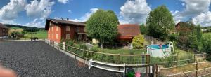 una casa con un patio vallado con parque infantil en Villa Kunterbunt en Grosswangen