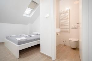 a white bathroom with a bed and a toilet at Velada Center in Hvar