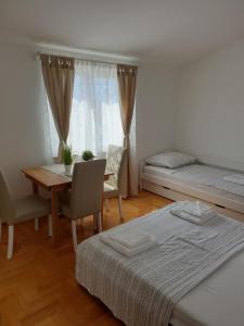 una camera con due letti, un tavolo e una finestra di Apartmani L&L Povljana a Povljana (Pogliana)