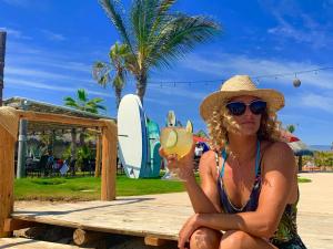 uma mulher sentada numa mesa de piquenique segurando uma bebida em Cerritos Surf Town - Beach Front Property em El Pescadero